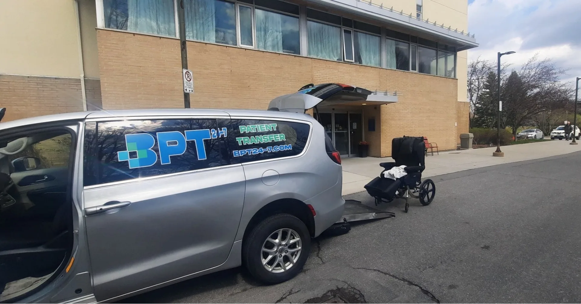 Patient in a BRODA reclining wheelchair being loaded through the rear ramp of a BPT24-7 patient transfer van in Ottawa