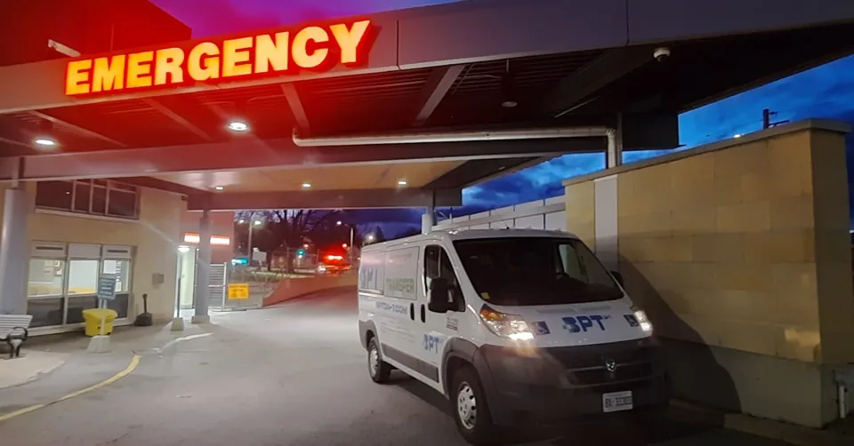 BPT24-7 stretcher transport van parked under the EMERGENCY canopy at an Ottawa hospital for a patient discharge transfer